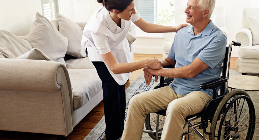 NDIS support worker assisting a man in a wheelchair at home